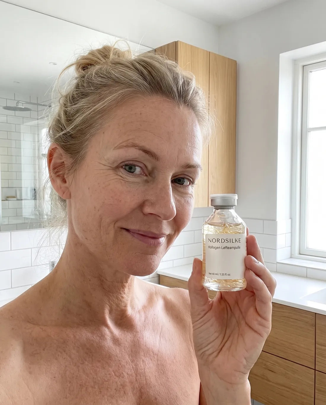 Kvinne i 50-årene holder Nordsilke-ampullen på badet